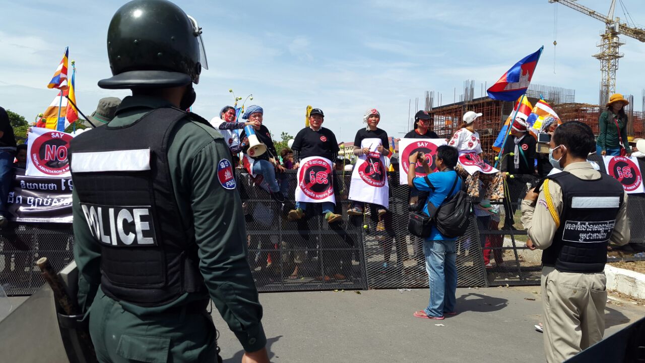 Protestors holding anti-LANGO signs are stand on a blockade across from police.